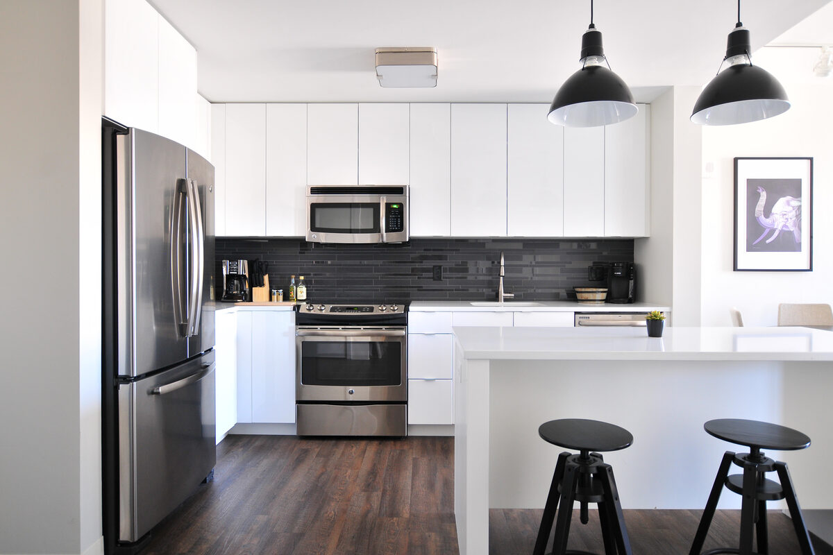 A spotless white kitchen with clear counters, stainless appliances and an island