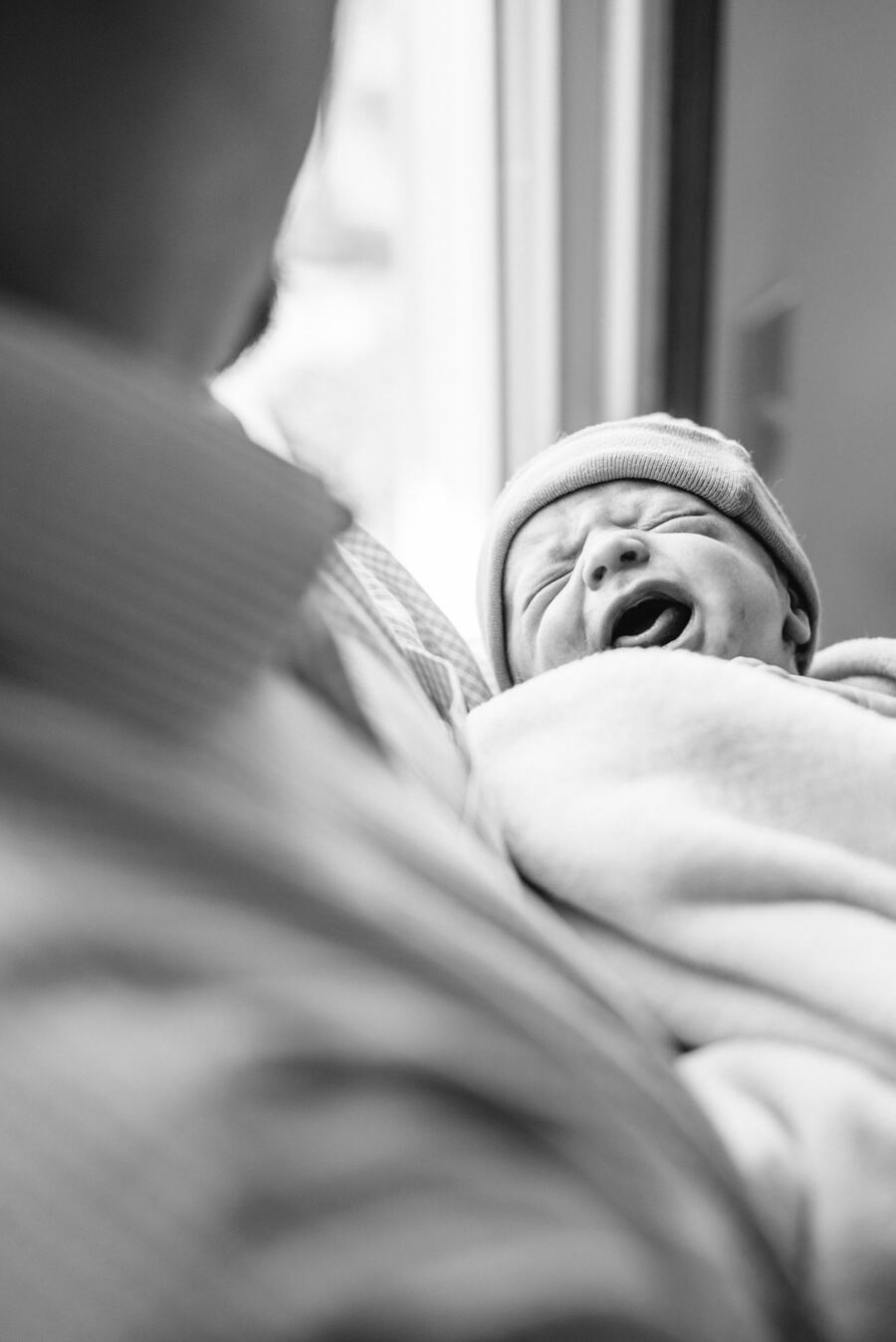 A newborn yawning in a parent's arms